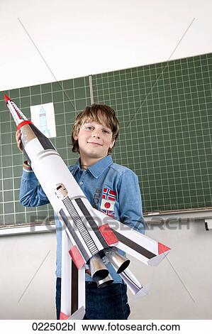 portrait of young boy in classroom holding model of rocket View Large Photo Image Stock Image - portrait of young boy in classroom holding model of rocket. Fotosearch