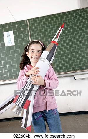 portrait of young girl in classroom holding model of rocket View Large Photo Image Stock Image - portrait of young girl in classroom holding model of rocket. Fotosearch
