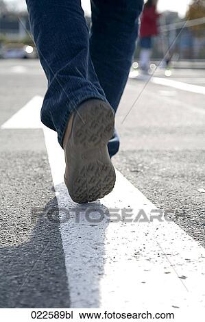 Stock Image - rear view of man walking in the street. Fotosearch