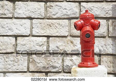 Stock Image - red fire hydrant in front of wall. Fotosearch