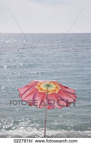 Stock Image - red sunshade on beach near Menton in France. Fotosearch