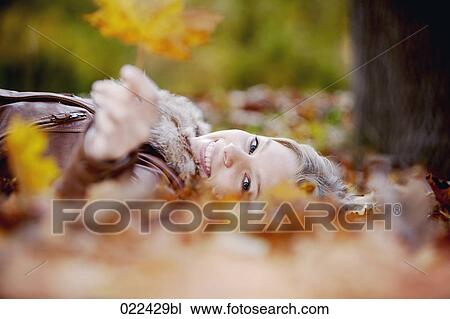 teenage girl lying on ground in autumn holding leaf View Large Photo Image Stock Image - teenage girl lying on ground in autumn holding leaf. Fotosearch