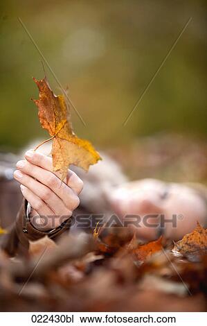 teenage girl lying on ground in autumn holding leaf View Large Photo Image Stock Image - teenage girl lying on ground in autumn holding leaf. Fotosearch