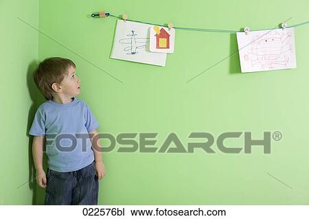 young boy looking at drawings hanging on wall View Large Photo Image Stock Image - young boy looking at drawings hanging on wall. Fotosearch
