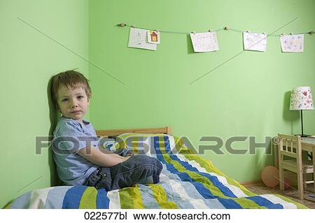 young boy sitting on bed in children´s room View Large Photo Image Stock Image - young boy sitting on bed in children´s room. Fotosearch