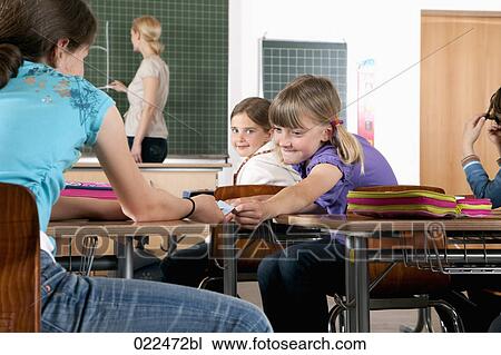 young girl giving little note to friend in classroom View Large Photo Image Stock Image - young girl giving little note to friend in classroom. Fotosearch