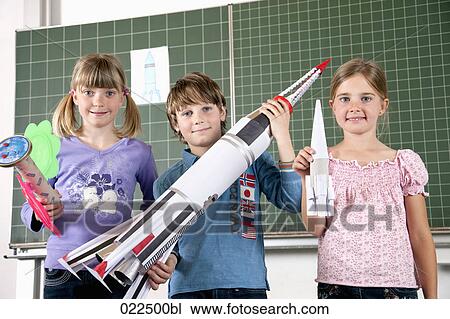 Stock Image - young pupils in classroom holding models of rockets. Fotosearch