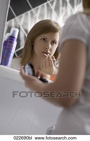 young woman in front of mirror applying lipstick View Large Photo Image Stock Image - young woman in front of mirror applying lipstick. Fotosearch