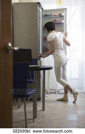 young woman in kitchen looking into open refrigerator View Large Photo Image Stock Image - young woman in kitchen looking into open refrigerator. Fotosearch