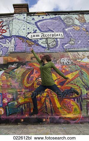 young woman jumping in front of colourful wall View Large Photo Image Stock Image - young woman jumping in front of colourful wall. Fotosearch