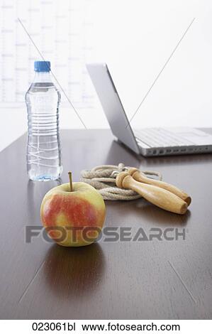 Stock Image - apple water bottle skipping rope and laptop computer on table. Fotosearch