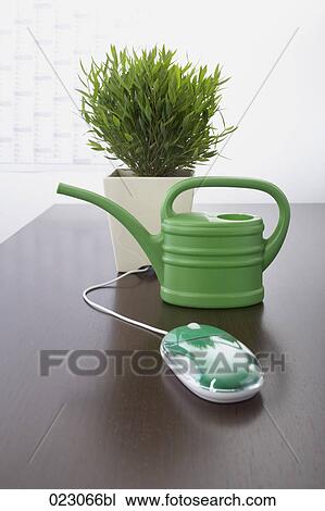 Stock Image - computer mouse watering can and potted plant on table. Fotosearch