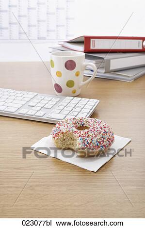 Stock Image - donut computer keyboard mug and folders on table. Fotosearch