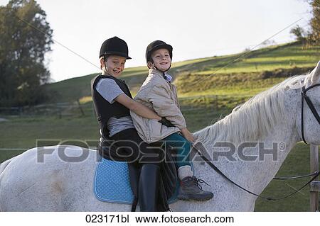 Portrait of two young boys sitting on white horse Stock Image