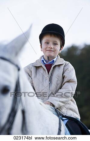 Stock Image - portrait of young boy sitting on white horse. Fotosearch