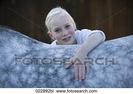 Stock Image - portrait of young girl caressing white horse. Fotosearch