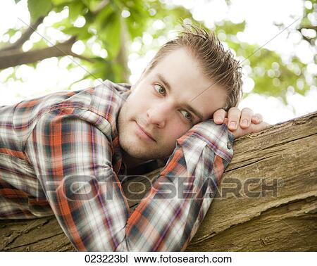 portrait of young man lying on tree trunk View Large Photo Image Stock Image - portrait of young man lying on tree trunk. Fotosearch