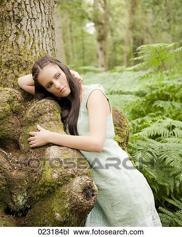 Stock Image - portrait of young woman leaning against tree. Fotosearch