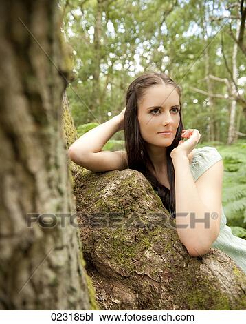 Stock Image - portrait of young woman leaning against tree. Fotosearch
