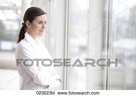 portrait of young woman standing at window View Large Photo Image Stock Image - portrait of young woman standing at window. Fotosearch