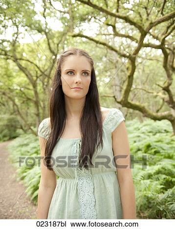 portrait of young woman standing in a forest View Large Photo Image Stock Image - portrait of young woman standing in a forest. Fotosearch