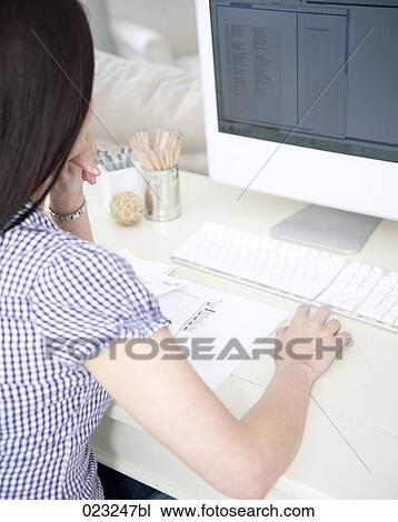 Stock Image - younf woman at home looking at computer screen. Fotosearch
