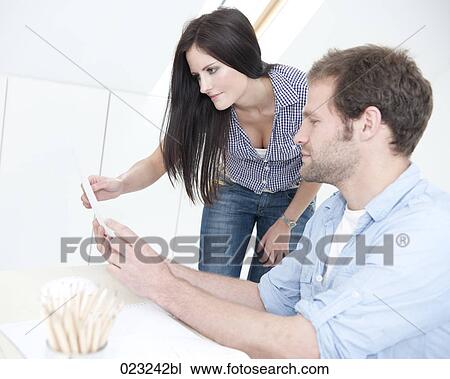 Stock Image - young couple at home studying document together. Fotosearch