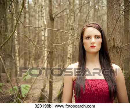 Stock Image - young woman in red dress in a forest. Fotosearch