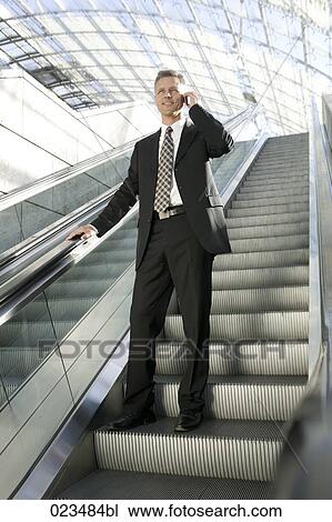 businessman standing on escalator talking on mobile phone View Large Photo Image Stock Image - businessman standing on escalator talking on mobile phone. Fotosearch