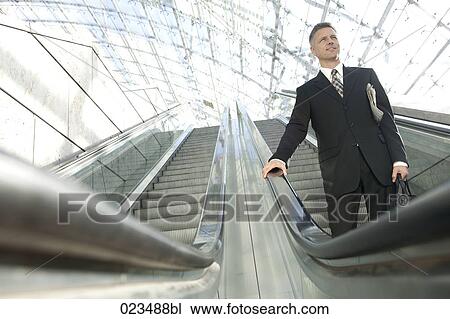 Stock Image - businessman standing on escalator. Fotosearch