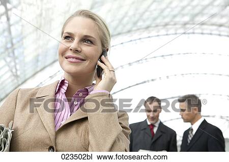 businesswoman talking on mobile phone with two businessmen in background View Large Photo Image Stock Image - businesswoman talking on mobile phone with two businessmen in background. Fotosearch
