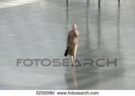 businesswoman walking through hall talking on mobile phone View Large Photo Image Stock Image - businesswoman walking through hall talking on mobile phone. Fotosearch
