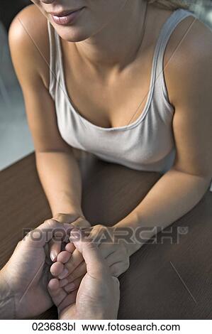 Stock Image - detail of young couple holding hands. Fotosearch