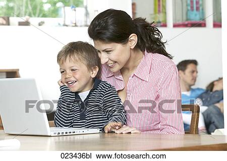 mother and young son at table in fron of laptop computer View Large Photo Image Stock Image - mother and young son at table in fron of laptop computer. Fotosearch