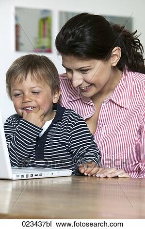 mother and young son at table in fron of laptop computer View Large Photo Image Stock Image - mother and young son at table in fron of laptop computer. Fotosearch