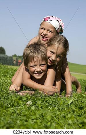 Stock Image - portrait of three children lying in grass. Fotosearch