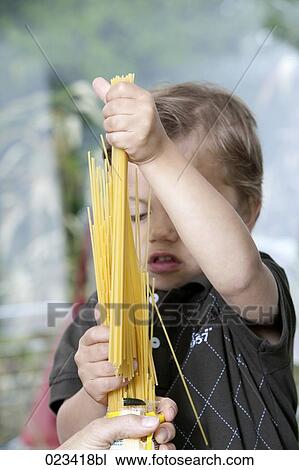 Stock Image - portrait of young boy holding spaghetti. Fotosearch