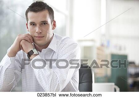 Stock Image - portrait of young businessman sitting at desk. Fotosearch