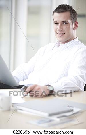 portrait of young businessman sitting at desk View Large Photo Image Stock Image - portrait of young businessman sitting at desk. Fotosearch