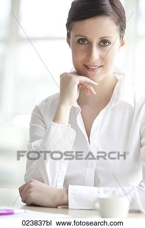 Stock Image - portrait of young businesswoman sitting at table. Fotosearch