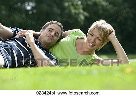 Stock Image - portrait of young couple lying in grass. Fotosearch
