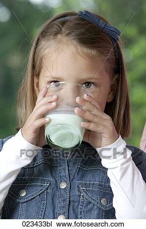 Stock Image - portrait of young girl drinking glass of milk. Fotosearch