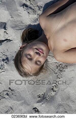 Stock Image - portrait of young girl lying on sand. Fotosearch