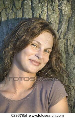 portrait of young woman leaning against tree View Large Photo Image Stock Image - portrait of young woman leaning against tree. Fotosearch