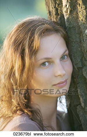 portrait of young woman leaning against tree View Large Photo Image Stock Image - portrait of young woman leaning against tree. Fotosearch