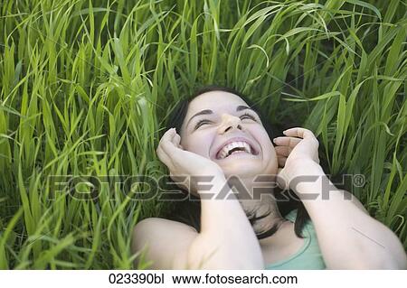 Stock Image - portrait of young woman lying in grass. Fotosearch