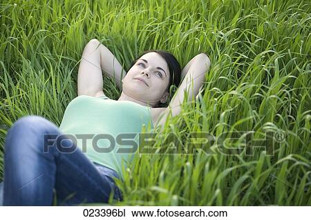 Stock Image - portrait of young woman lying in grass. Fotosearch