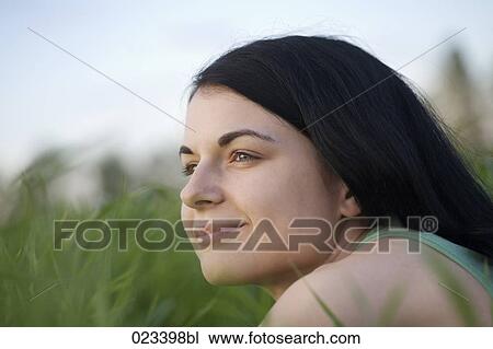 Stock Image - portrait of young woman lying in grass. Fotosearch