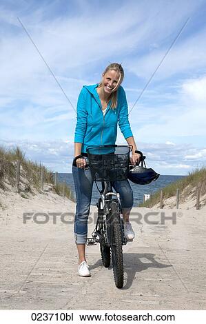 Stock Image - portrait of young woman on bicycle at beach. Fotosearch