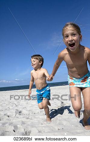 Stock Image - sister and brother running on beach in summer. Fotosearch